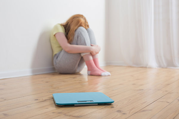 sad-teenager-girl-with-scale-wooden-floor